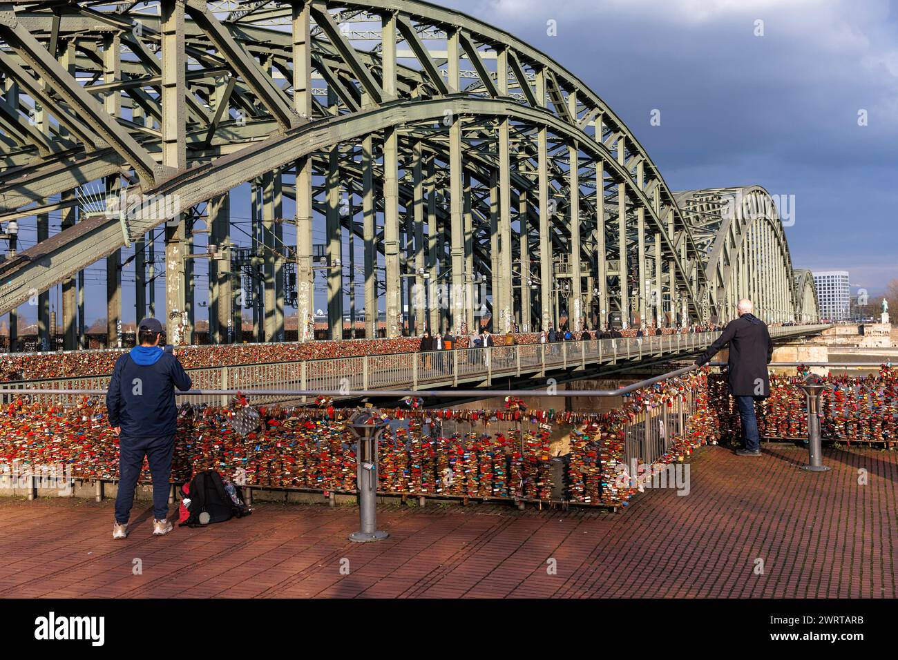 Deux hommes debout à la clôture avec les écluses d'amour au pont Hohenzollern, Cologne, Allemagne. zwei Maenner stehen am Zaun mit den Liebesschloessern an d. Banque D'Images