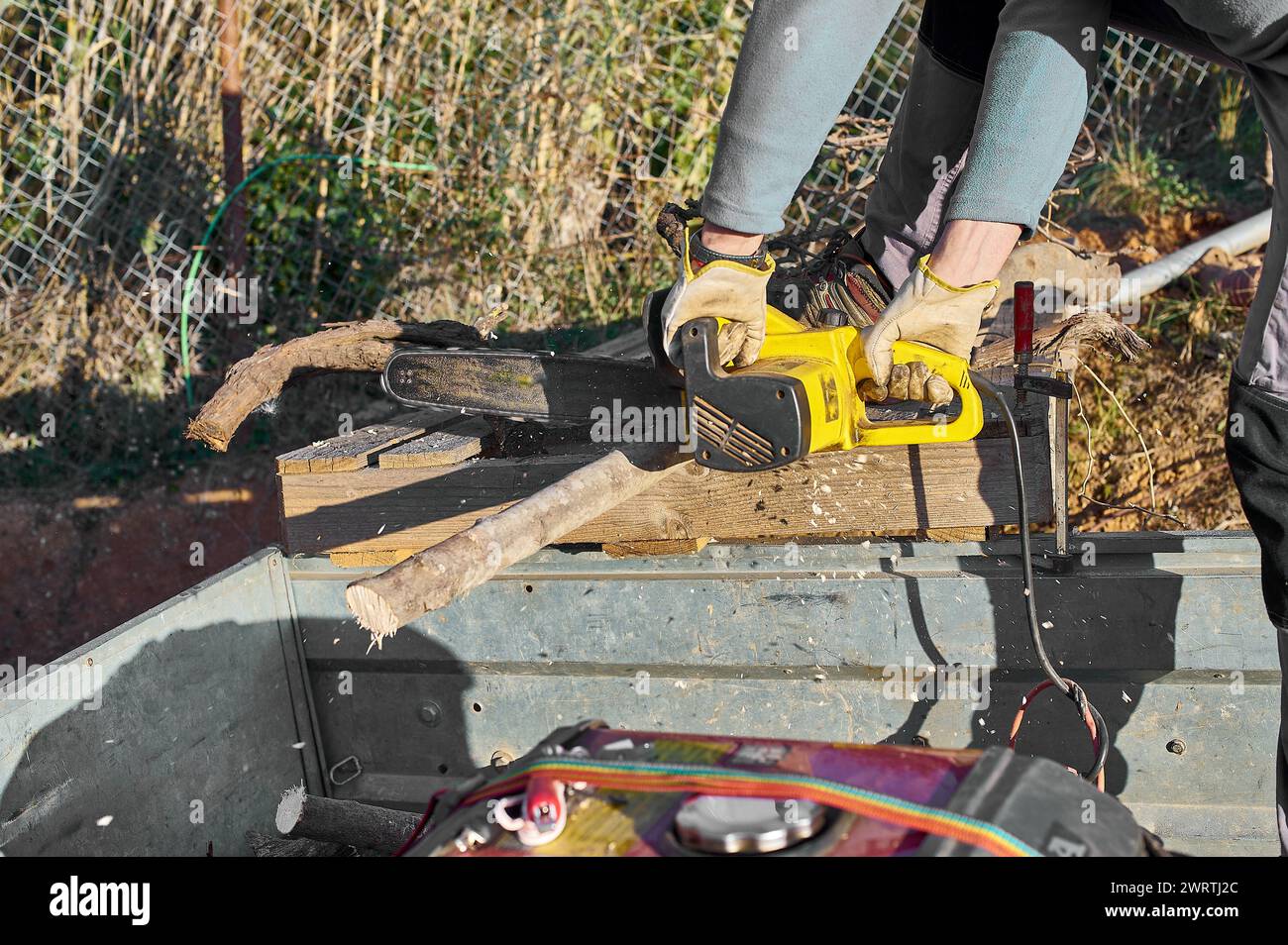 Travailleur coupant du bois à l'extérieur avec une tronçonneuse, concentré et efficace. Banque D'Images
