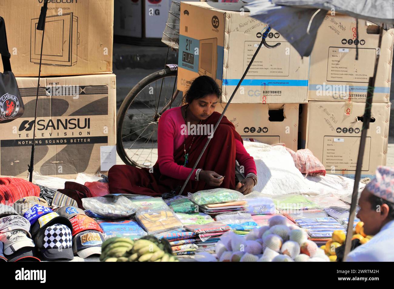 Une femme vend des marchandises sur le sol d'une rue de la ville sous un grand parapluie, Bhairahawa, Népal Banque D'Images Une femme vend des marchandises sur le sol d'une rue de la ville sous un grand parapluie, Bhairahawa, Népal Banque D'Images