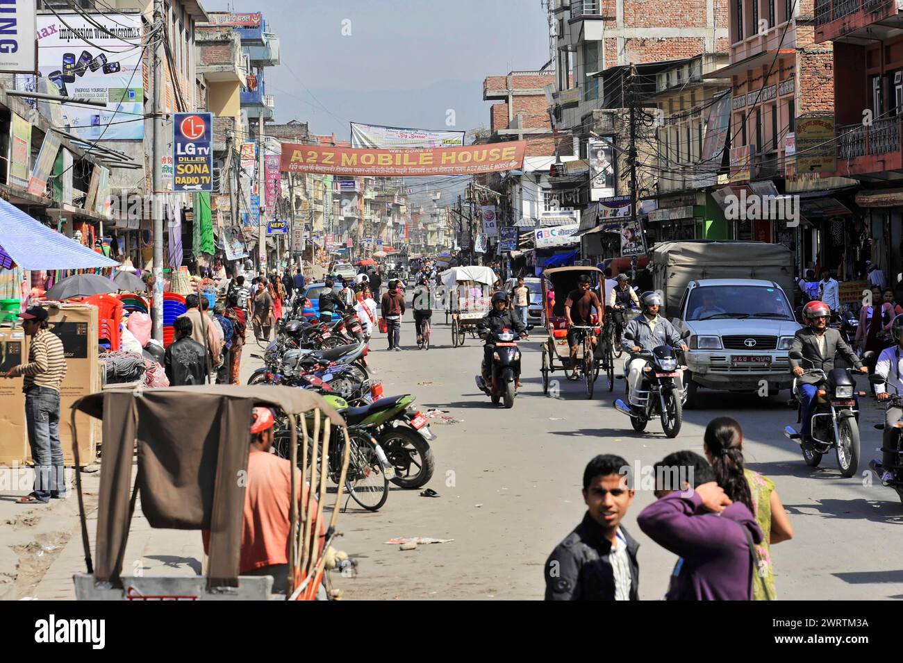 Rue urbaine animée avec des gens et des véhicules sous un ciel clair, Bhairahawa, Népal Banque D'Images
