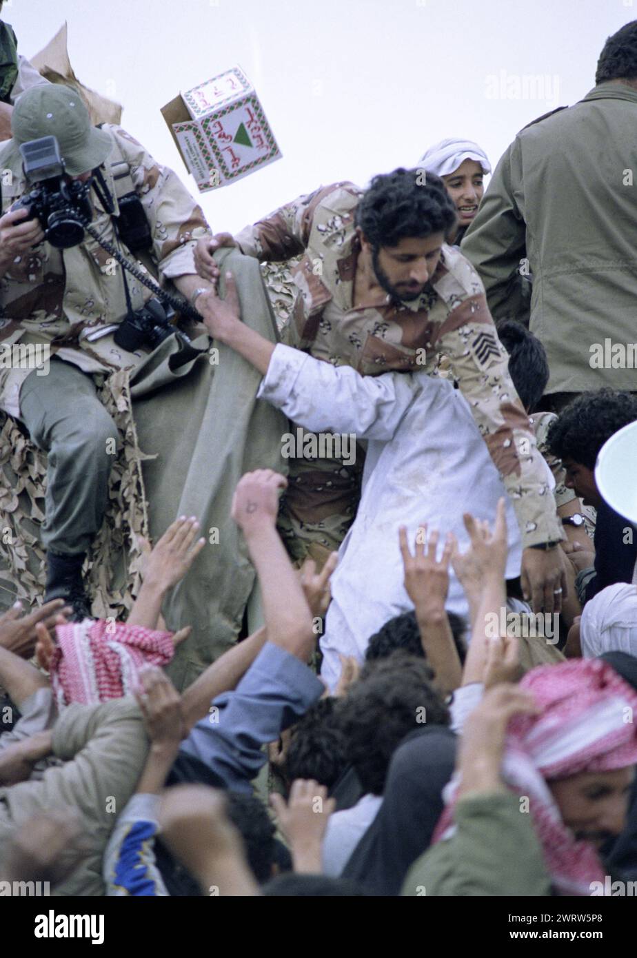 23 mars 1991 des soldats saoudiens distribuent de la nourriture et des boissons aux Chiites Irakiens désespérés près de Safwan, près de la frontière avec le Koweït. Banque D'Images