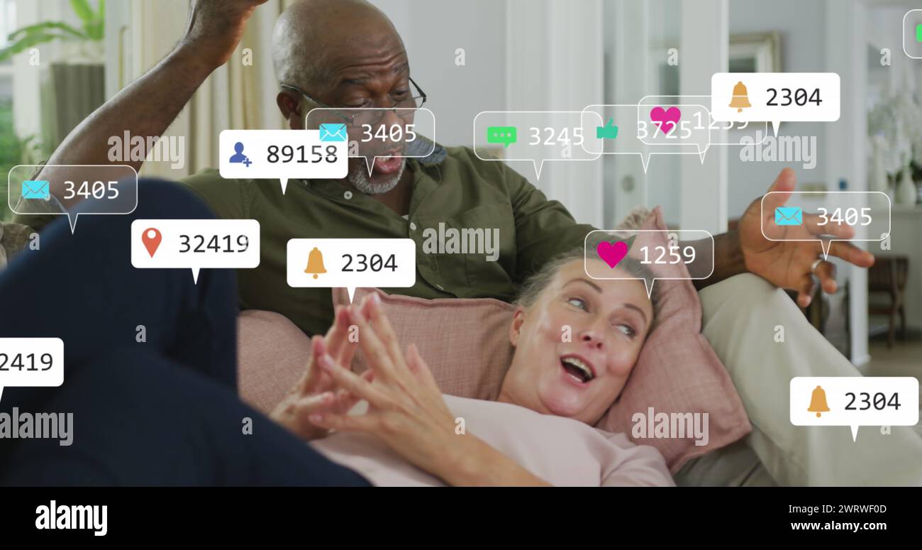Image d'icônes et de chiffres de médias sociaux sur un couple senior diversifié à la maison Banque D'Images