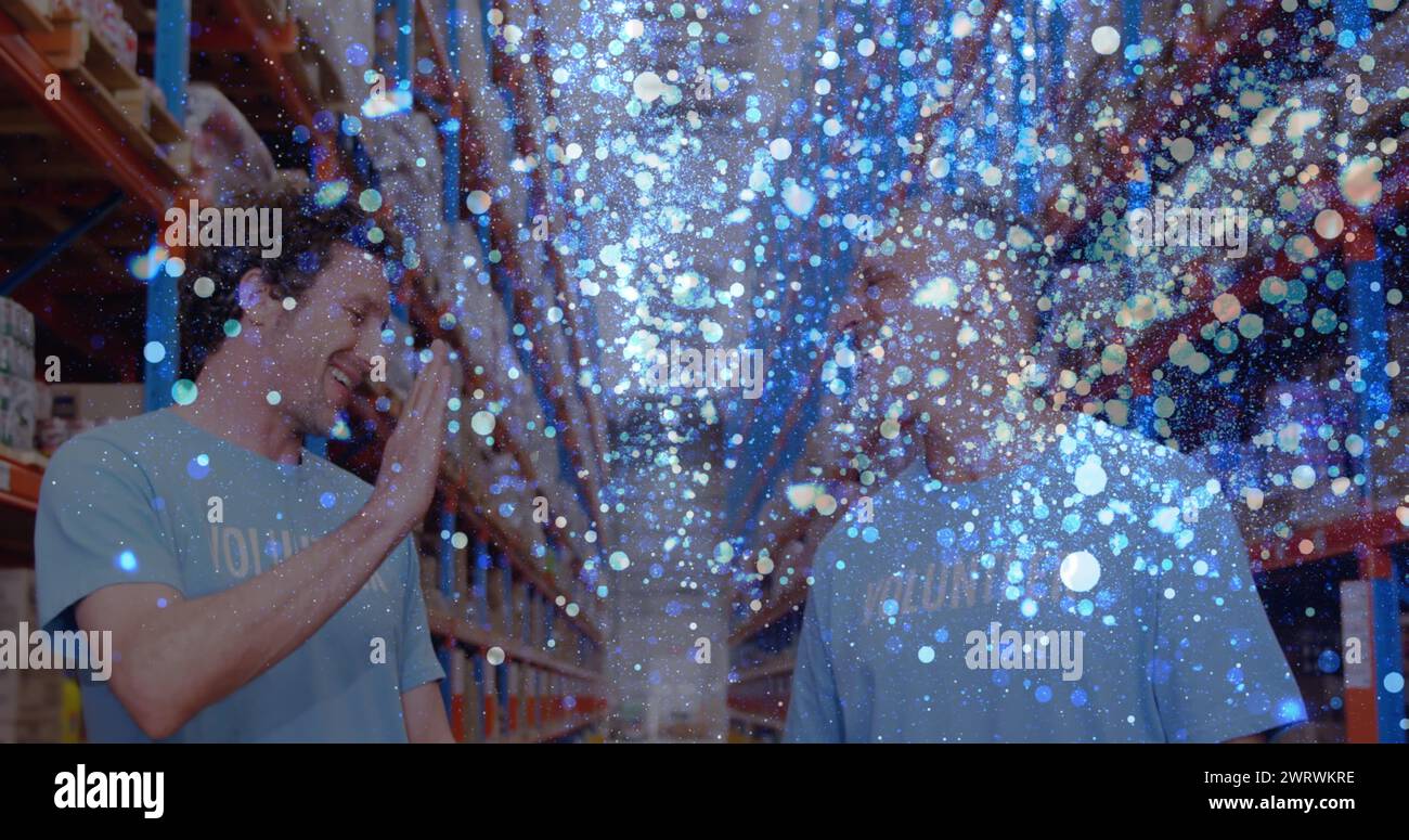 Image de taches de lumière brillantes sur des hommes caucasiens en bénévolat dans l'entrepôt, Banque D'Images