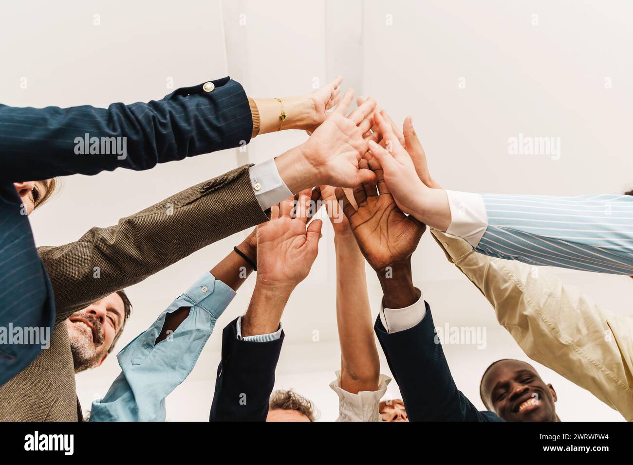 Équipe d'affaires diversifiée se joignant les mains dans un geste de cinq hauts, symbolisant l'unité et le succès dans un environnement d'entreprise. Banque D'Images