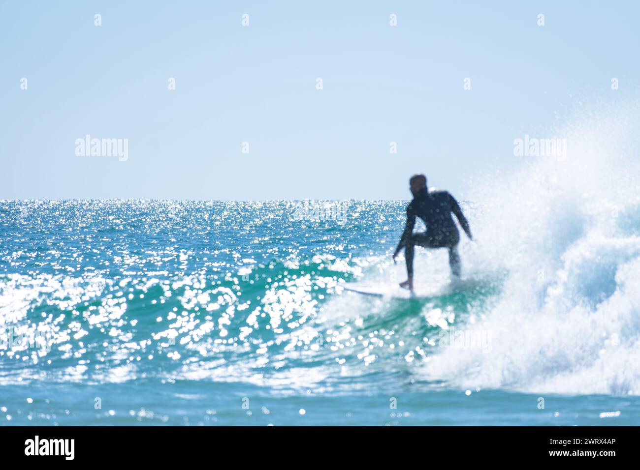 Homme noir défocalisé surfant dans l'eau bleue de l'océan Pacifique Banque D'Images