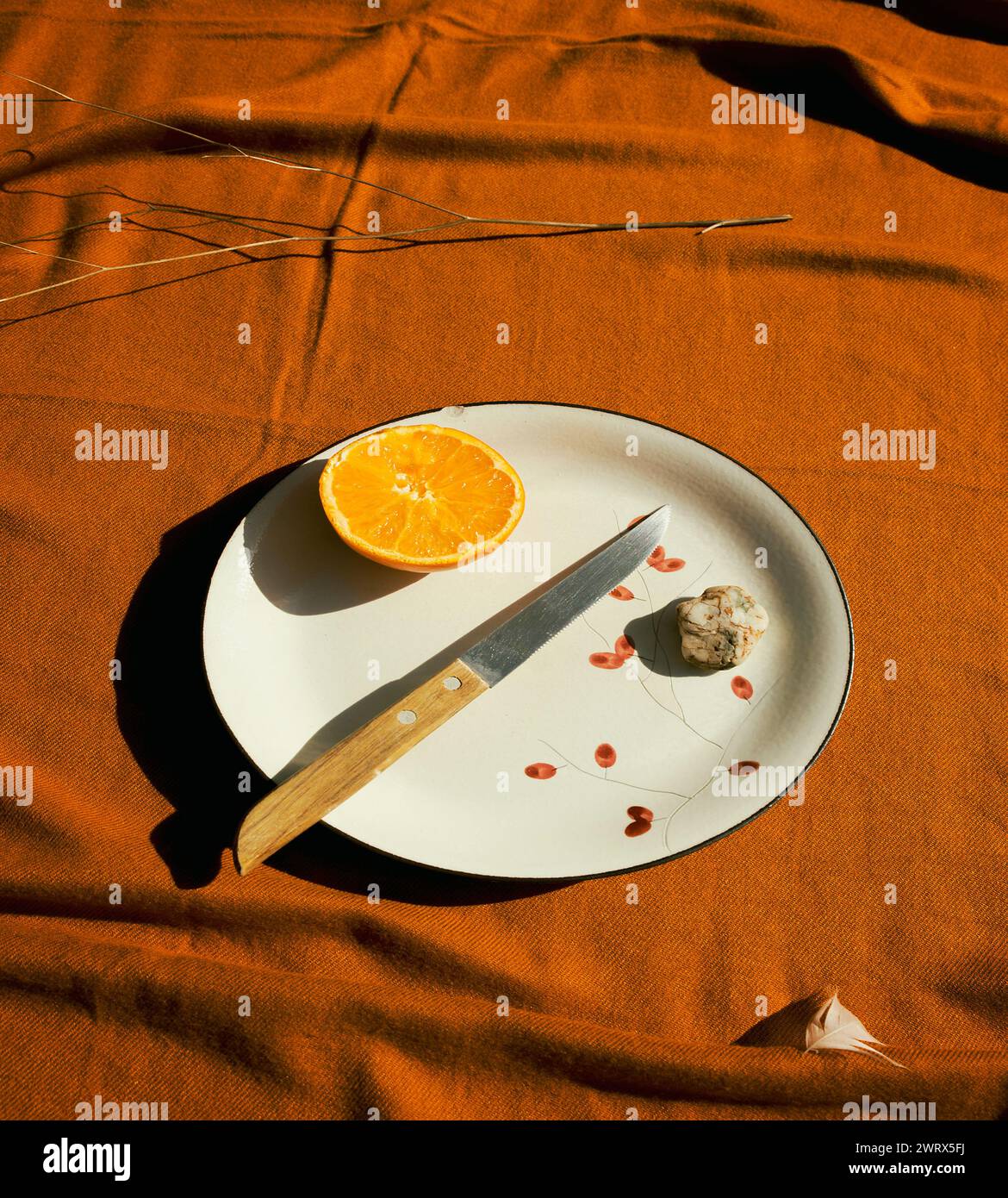 assiette avec une demi-orange et couteau sur une écharpe orange Banque D'Images