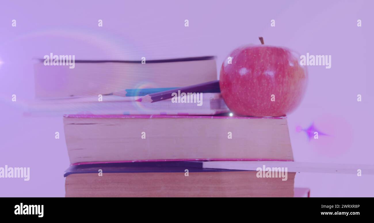 Image d'une lumière brillante au-dessus d'une pomme sur une pile de livres Banque D'Images