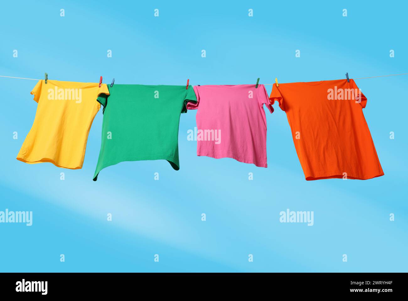 T-shirts colorés séchant sur la ligne de lavage contre le ciel bleu, vue d'angle bas Banque D'Images T-shirts colorés séchant sur la ligne de lavage contre le ciel bleu, vue d'angle bas Banque D'Images