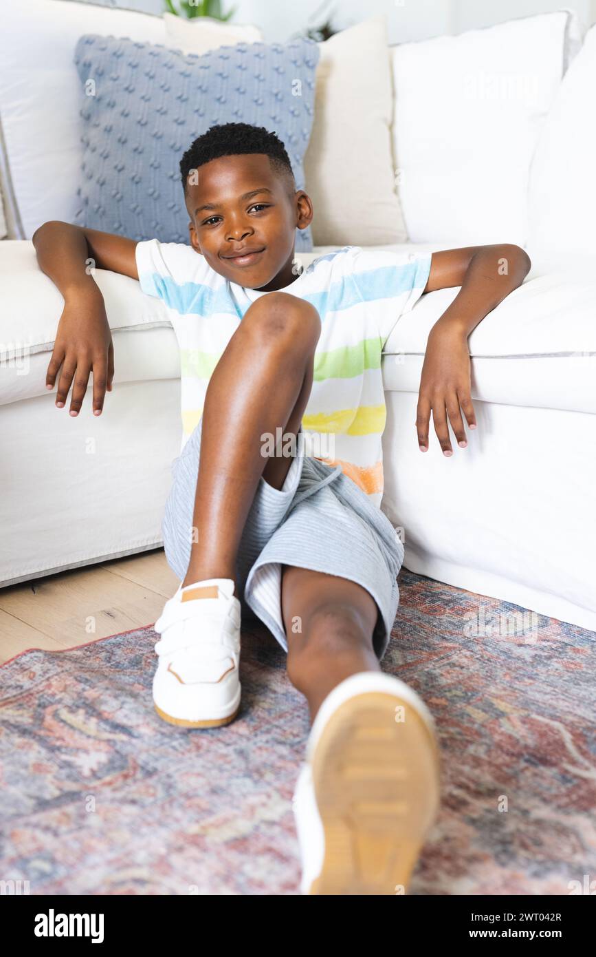 Un jeune garçon afro-américain se prélasse confortablement sur le sol à la maison Banque D'Images