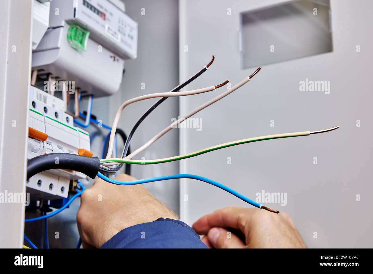 Travaux électriques sur la connexion d'un câble d'alimentation triphasé au réseau électrique domestique dans un panneau électrique. Banque D'Images