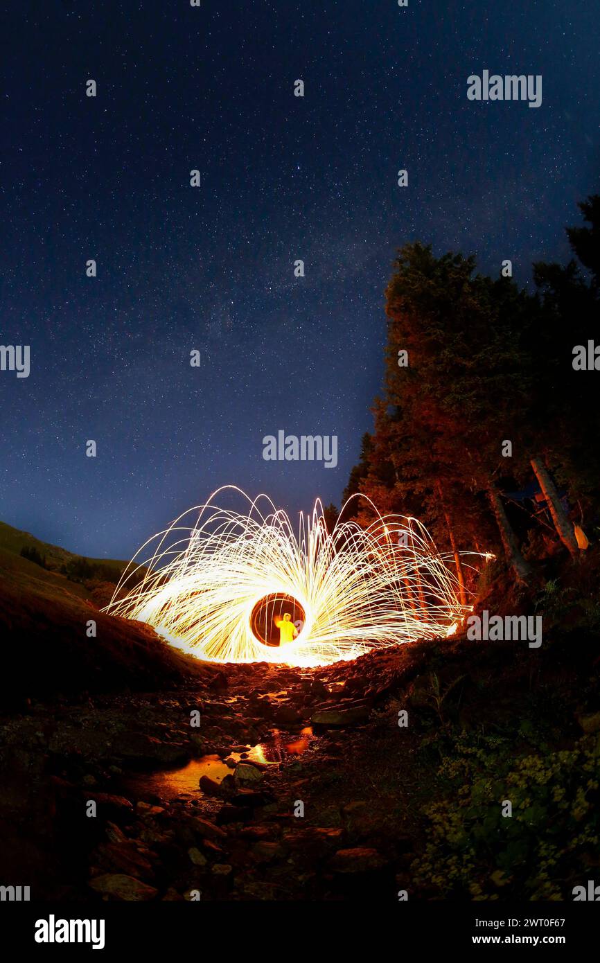 Une personne créant des traînées de lumière avec un orbe dans une prise de vue longue exposition Banque D'Images