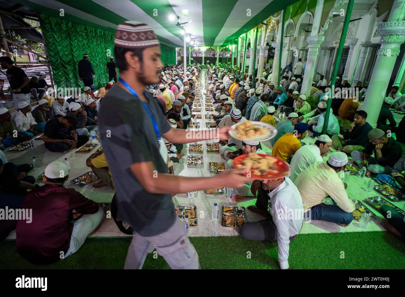 Des bénévoles distribuent et organisent des rangées de repas 'iftar' pour les dévots afin de rompre leur jeûne, pendant le mois sacré du Ramadan, à Burha Jame Masjid, on Banque D'Images