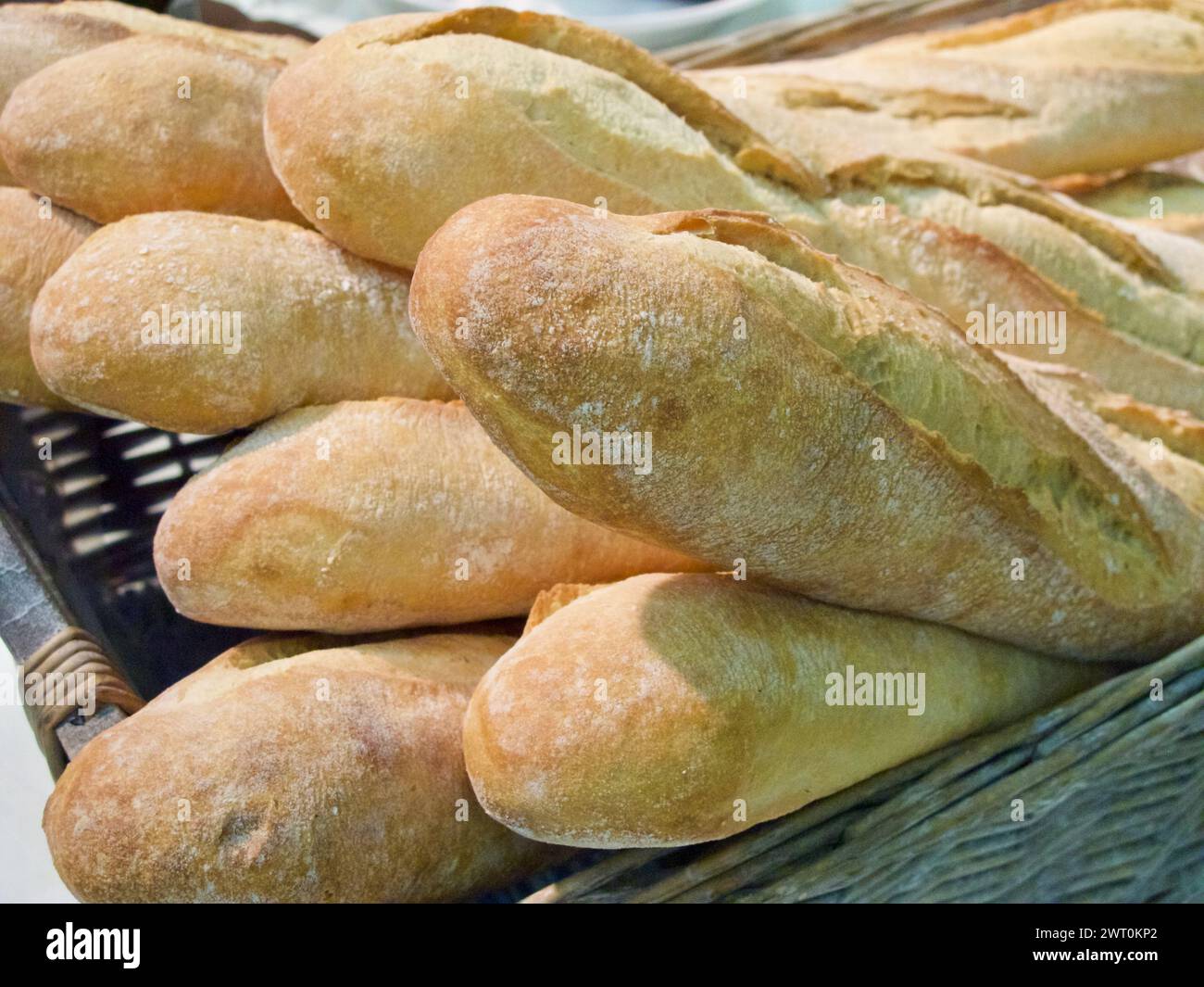 Baguettes complètes fraîchement biologiques dans un panier à pain tressé. Banque D'Images