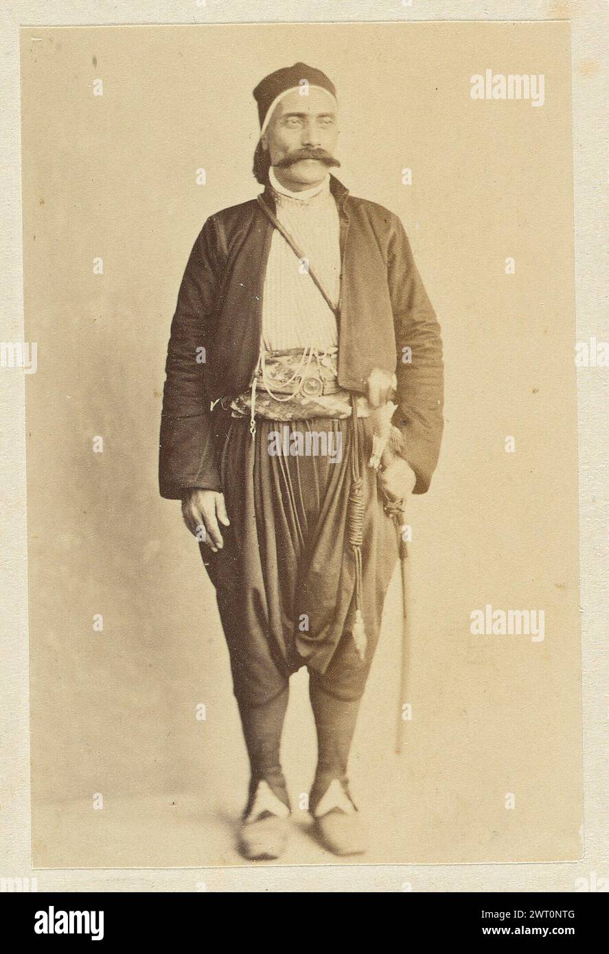 Portrait d'un homme. Wilhelm Hammerschmidt, photographe (allemand, né en Prusse, mort en 1869) années 1860 Un homme pose dans un espace intérieur devant un mur blanc. L'homme a une moustache et porte une épée à la ceinture, un pantalon sombre et ample et une veste noire. Banque D'Images