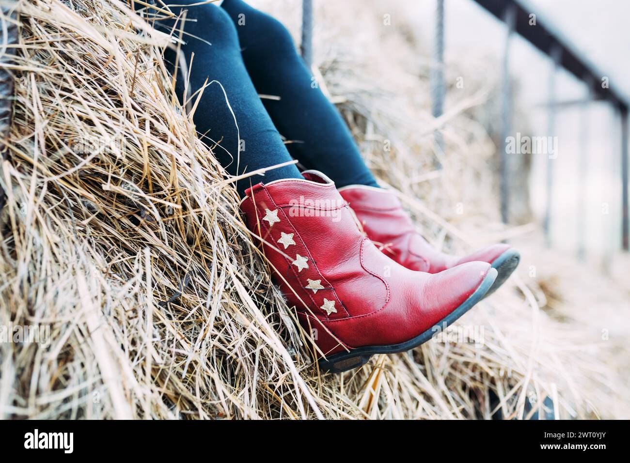 Enfant portant des bottes de cow-boy rouges avec des étoiles assis sur la balle de foin Banque D'Images