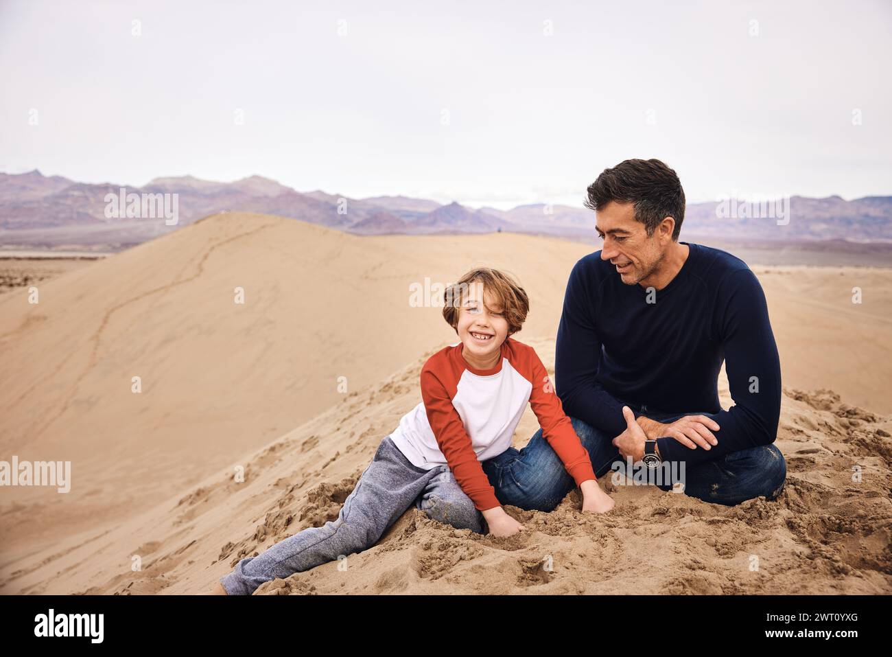Fils heureux assis avec son père sur une dune de sable à Death Valley Banque D'Images