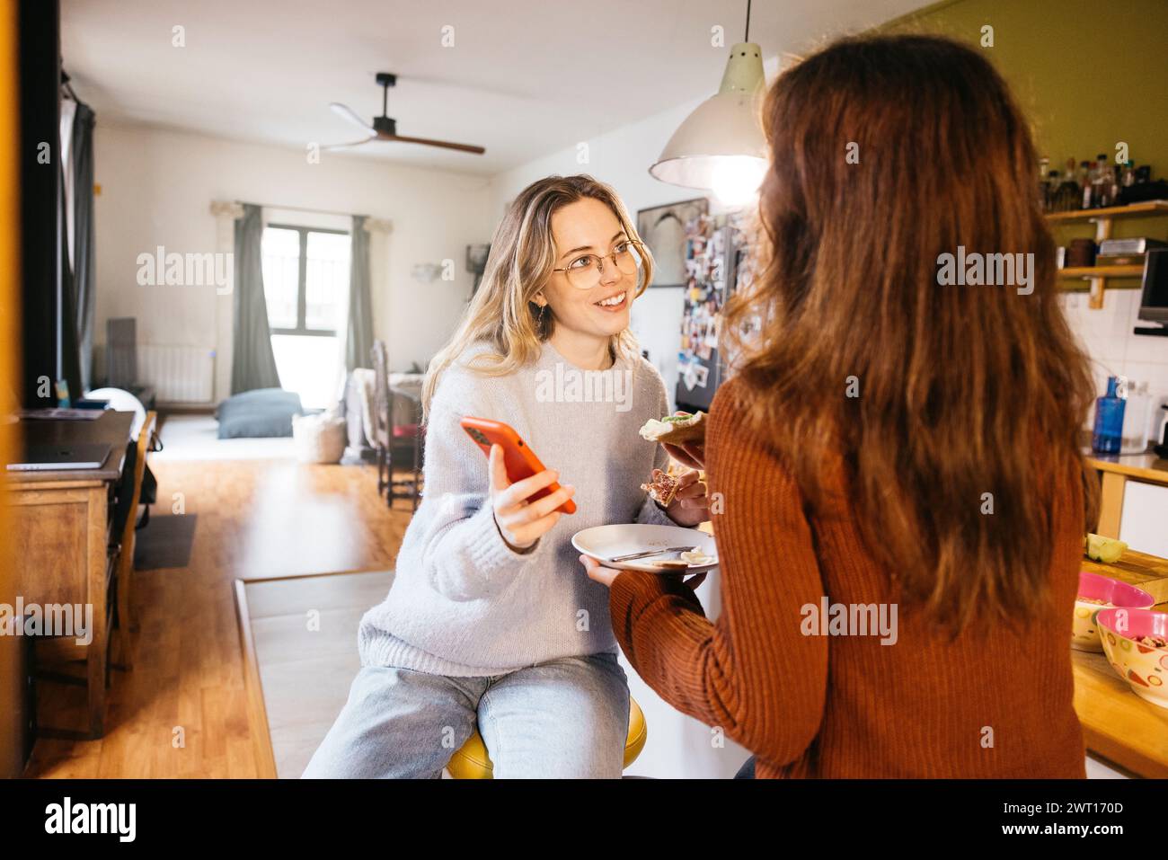 Un couple de lesbiennes prenant le petit déjeuner et partageant un moment intime ensemble, dans l'atmosphère chaleureuse de leur cuisine à la maison. Banque D'Images