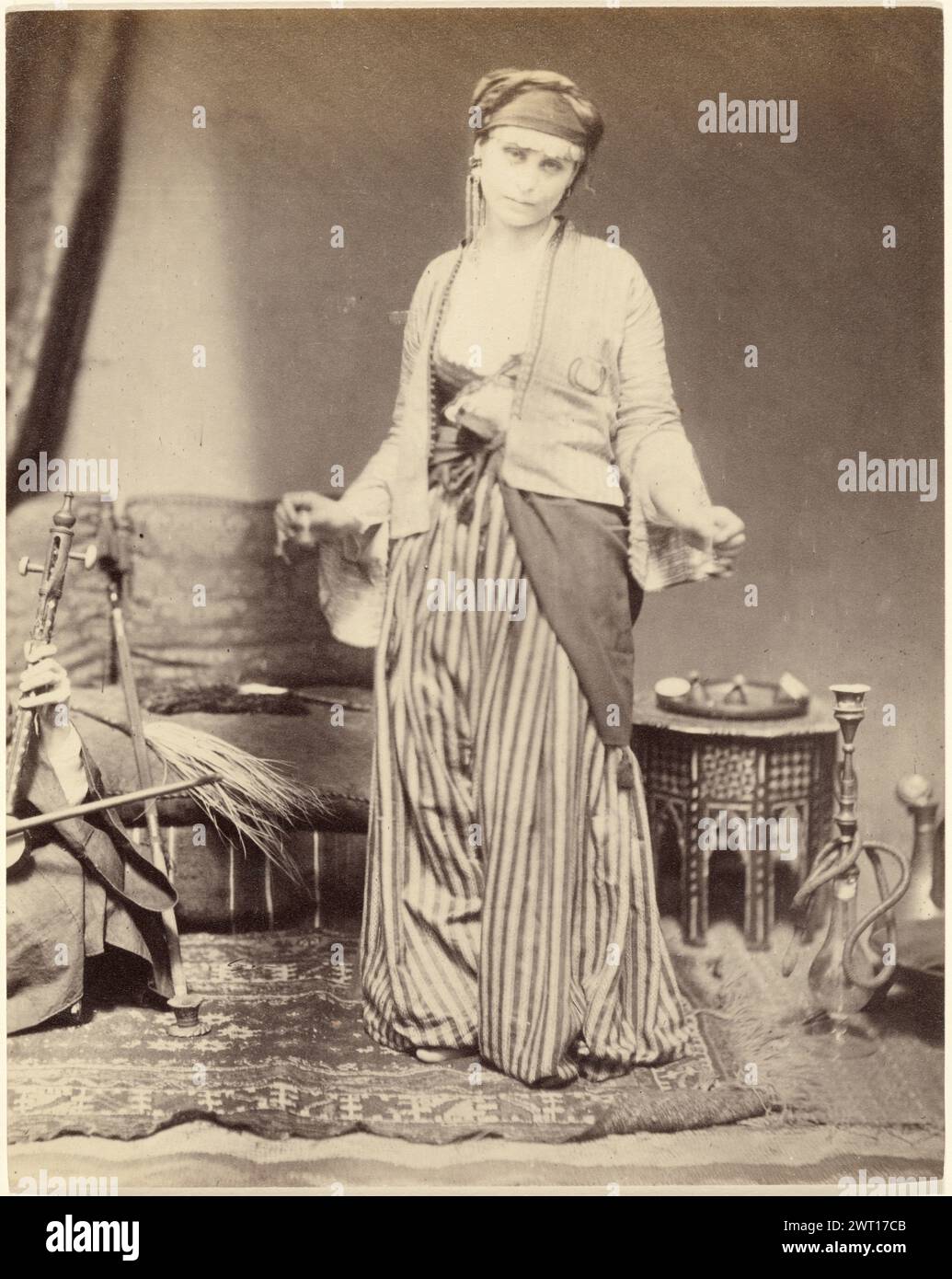 Fille danseuse égyptienne. Roger Fenton, photographe (anglais, 1819 - 1869) 1858 dans les années 1800, un intérêt croissant pour ce qui était considéré comme des terres exotiques a engendré une prolifération d'images et de textes qui traitaient de l'individu étranger comme du mystérieux «autre». Bien que déguisée en danseuse égyptienne, cette femme est en fait un mannequin anglais posant dans le studio londonien de Roger Fenton. Incapable de capturer la femme qui danse puisque le mouvement rendrait l'image floue, le photographe a plutôt montré divers instruments de musique associés à la danse. Banque D'Images