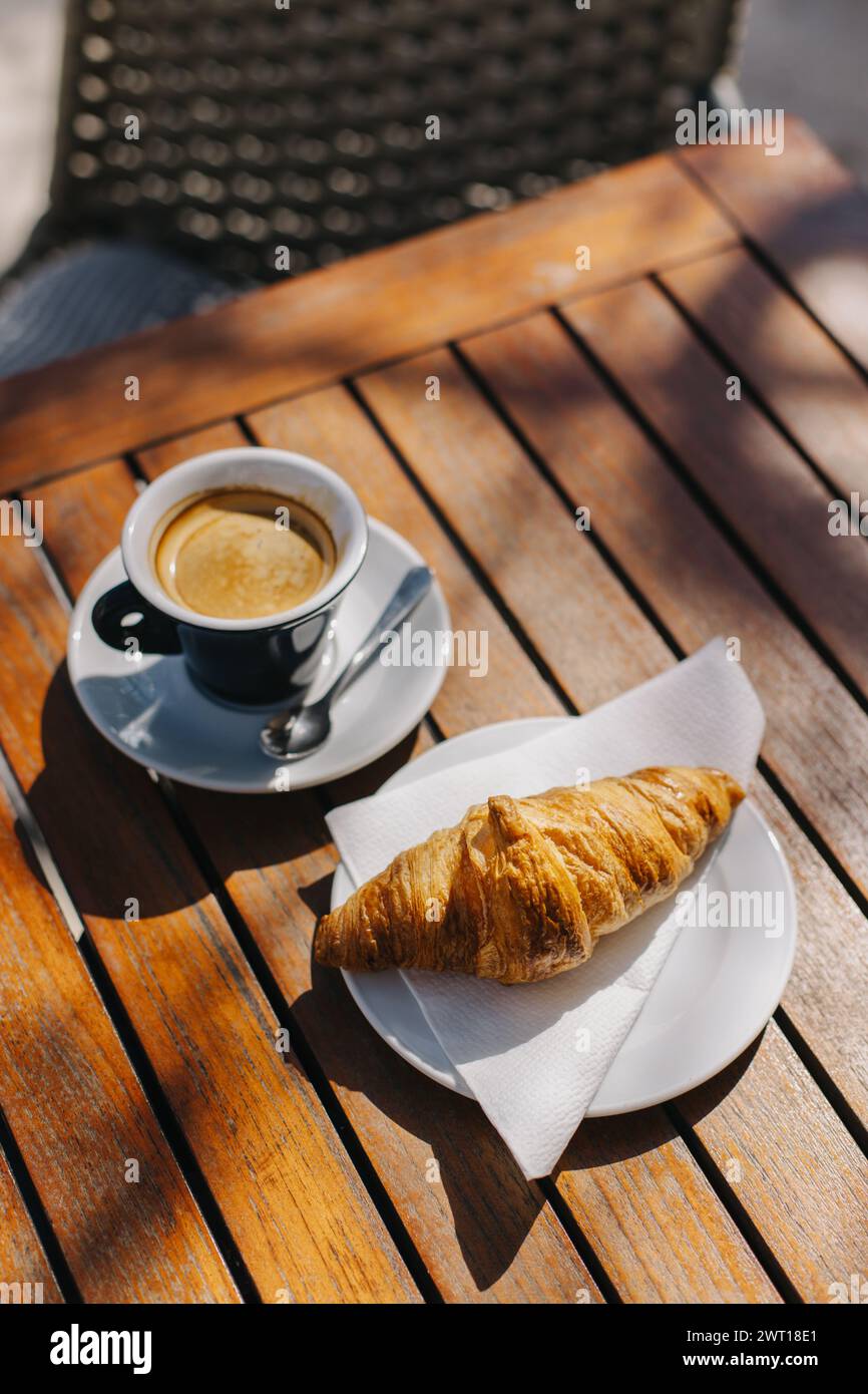 Une tasse de café noir et un croissant sur une table dans un café de rue. Mise au point sélective. Placer pour le texte. Banque D'Images