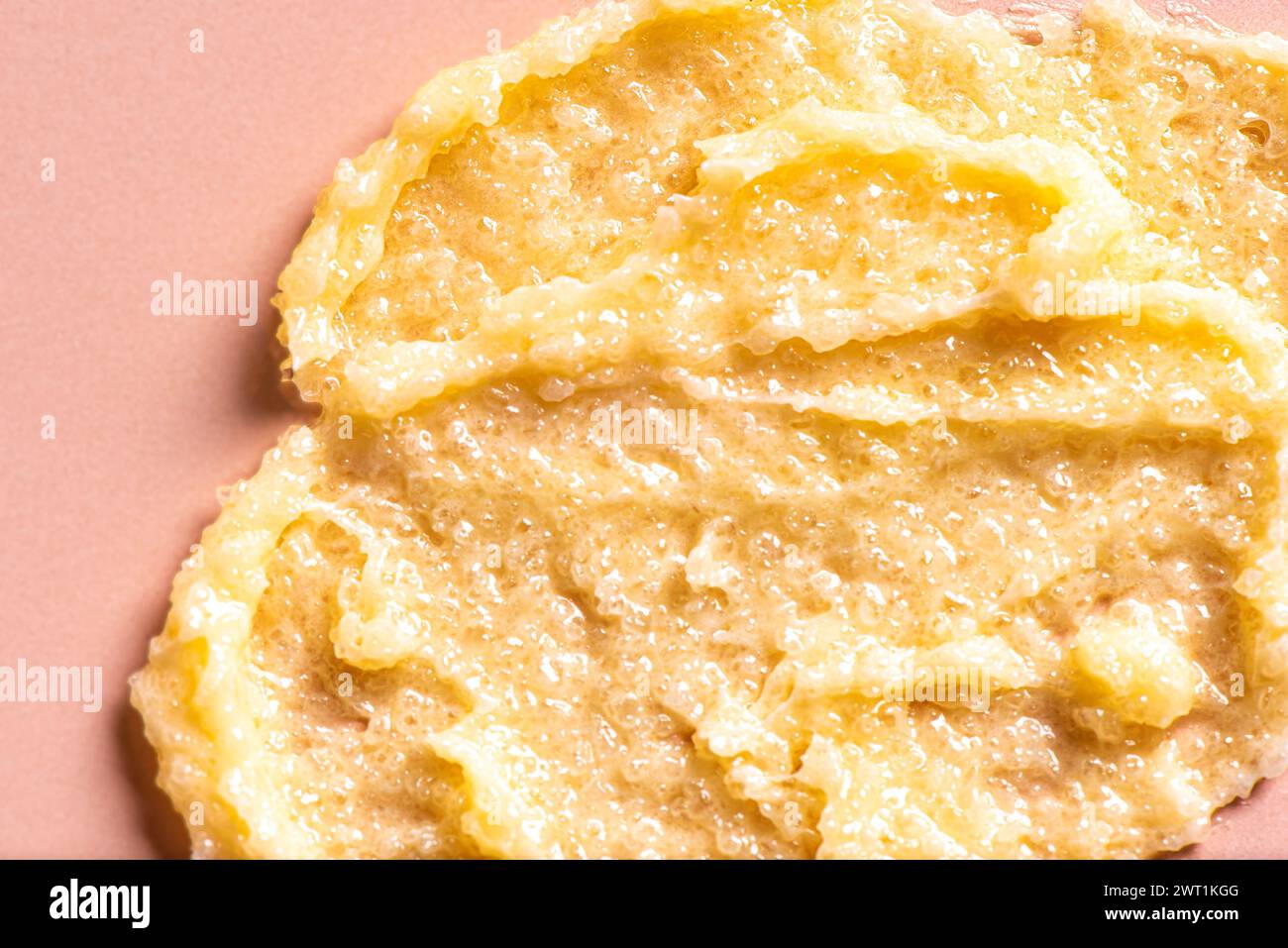 Maculage au sucre jaune maculage isolé sur fond rose beige. Texture du gommage corporel avec du sel ou du sucre. Banque D'Images