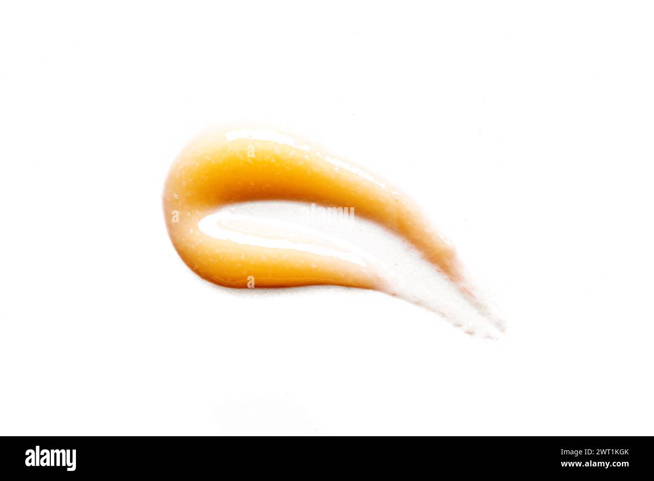Échantillon de gel orange isolé sur fond blanc, gros plan. Texture du produit cosmétique orange pour le soin des cheveux du visage. Banque D'Images