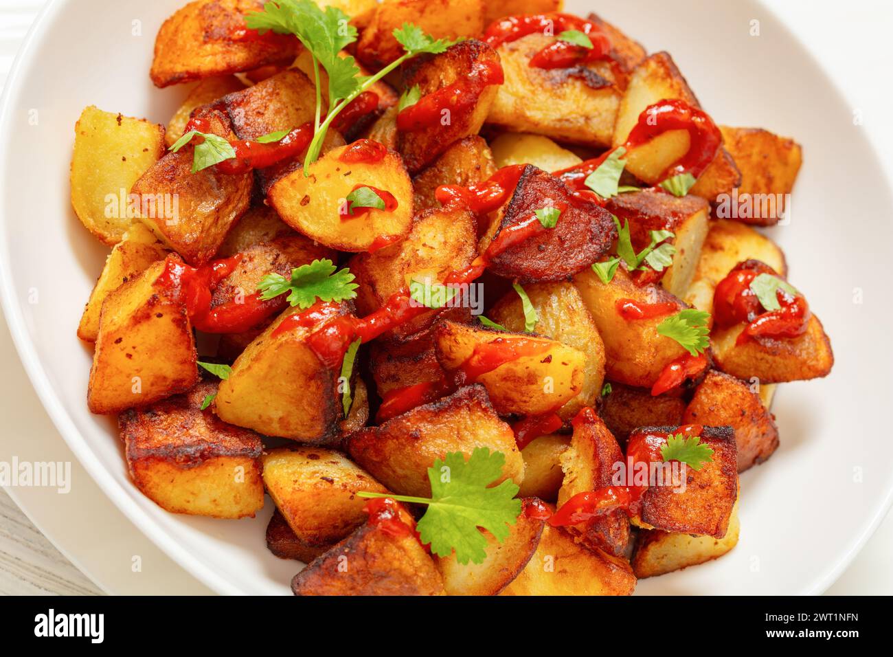 patata bravas frites croustillantes, pommes de terre espagnoles frites avec sauce paprika fumée dans un bol blanc, gros plan Banque D'Images