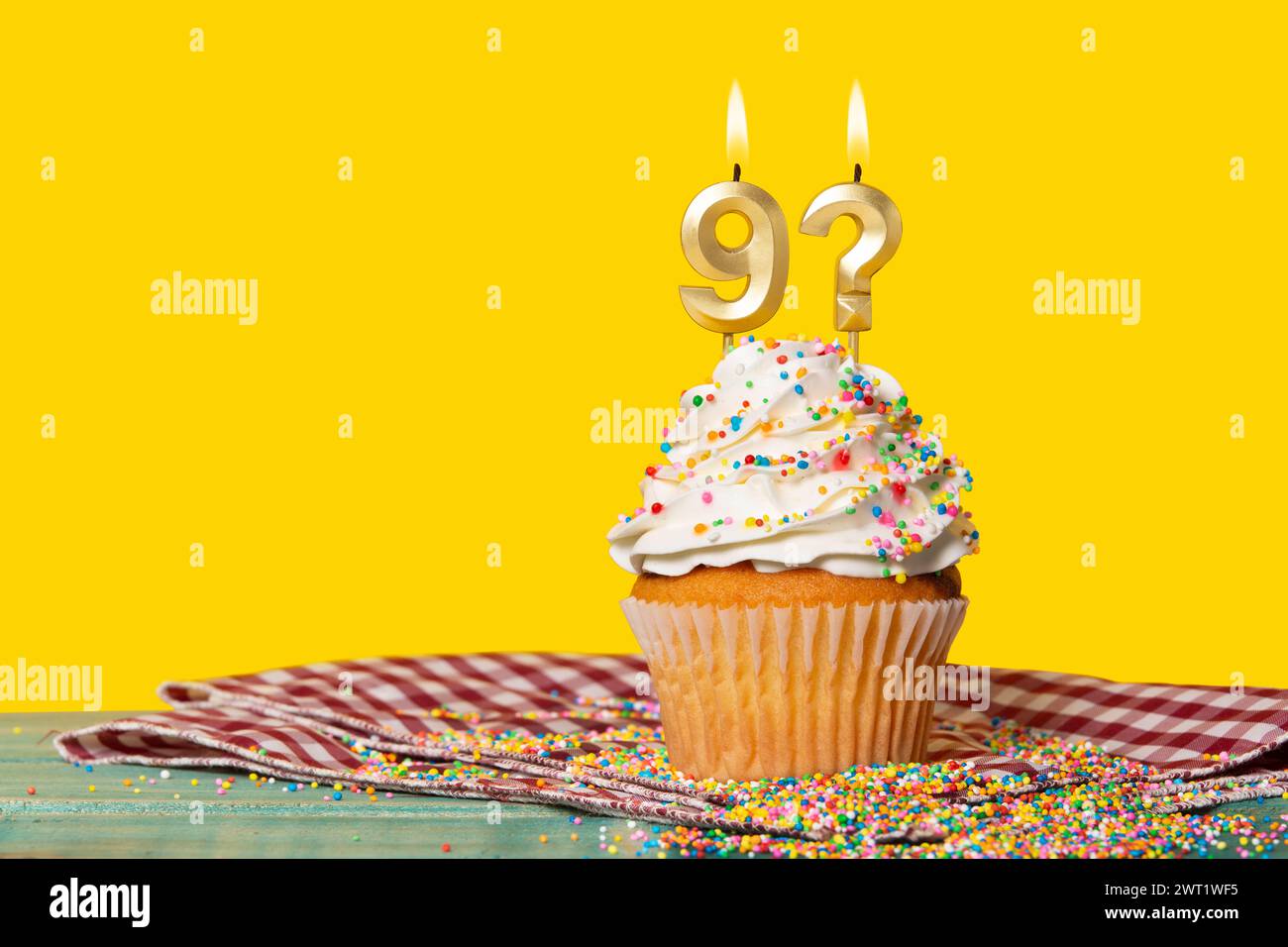 Cupcake d'anniversaire avec bougie numéro 9 et point d'interrogation - photo sur fond jaune. Banque D'Images