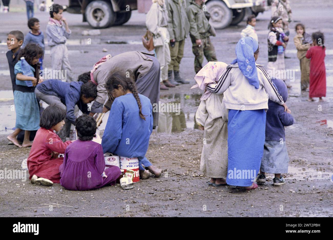 23 mars 1991 des enfants chiites irakiens se blottissent entre les flaques d'eau dans un camp de réfugiés près de Safwan dans le sud de l'Irak, près de la frontière avec le Koweït. Banque D'Images