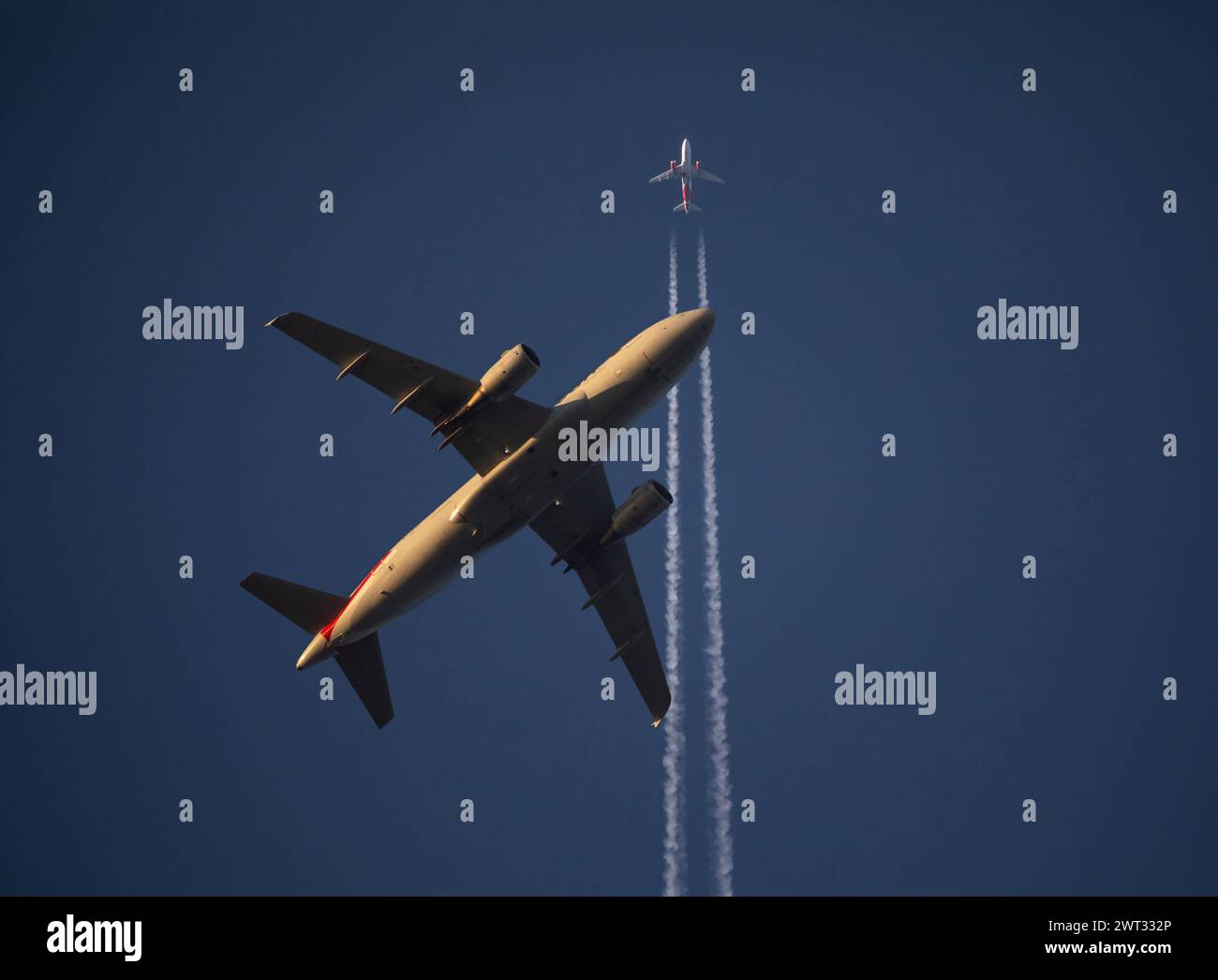 Un avion de ligne commercial à basse altitude passe sous un avion de ligne à haute altitude peu après son décollage au coucher du soleil. Banque D'Images