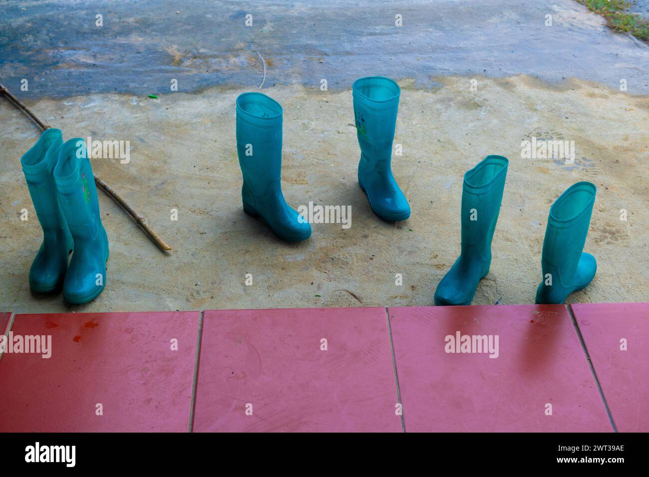 Nature morte de carreaux rouges et trois paires de bottes bleues, en caoutchouc, imperméables portées par les femmes Hmong qui guident les treks à travers la montagne humide et boueuse regi Banque D'Images