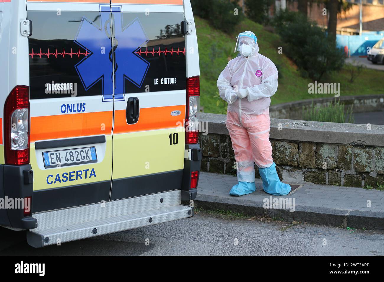 Un médecin, vêtu d'un ensemble et de masques pour se protéger, près d'une ambulance placée devant l'hôpital de Cosugno à Naples, avec un patient en attente Banque D'Images