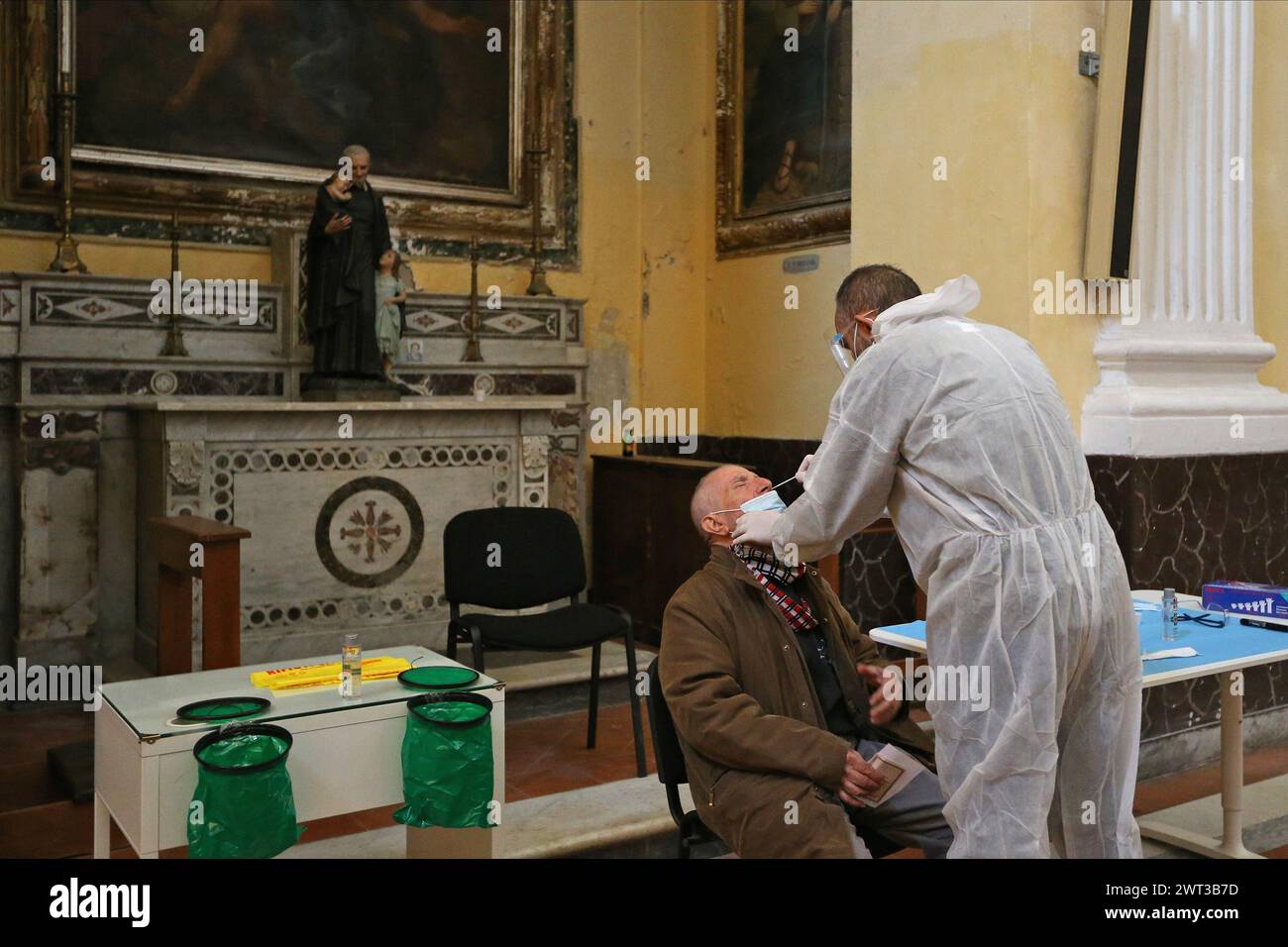 Un médecin, vêtu d'un ensemble et d'un masque pour se protéger, tout en buvant un homme, au cours de l'initiative la solidarité et suspendu Swab. Un cri vif Banque D'Images