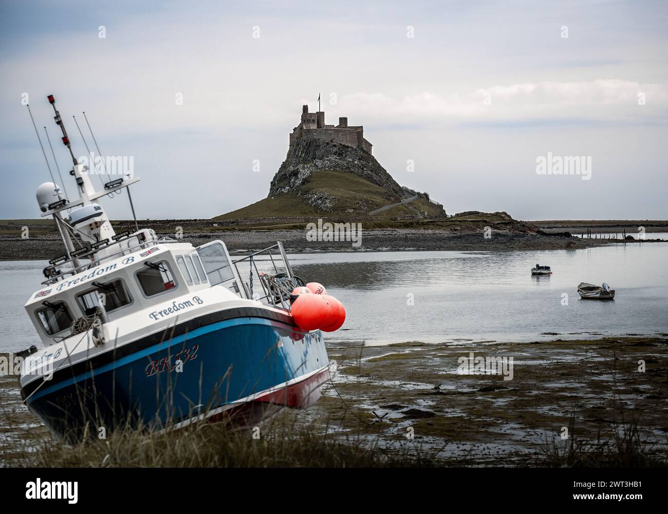 Château et port de Lindisfarne avec bateaux de pêche au premier plan Banque D'Images