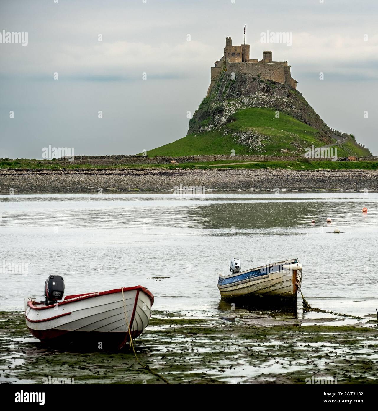 Château et port de Lindisfarne avec bateaux de pêche au premier plan Banque D'Images