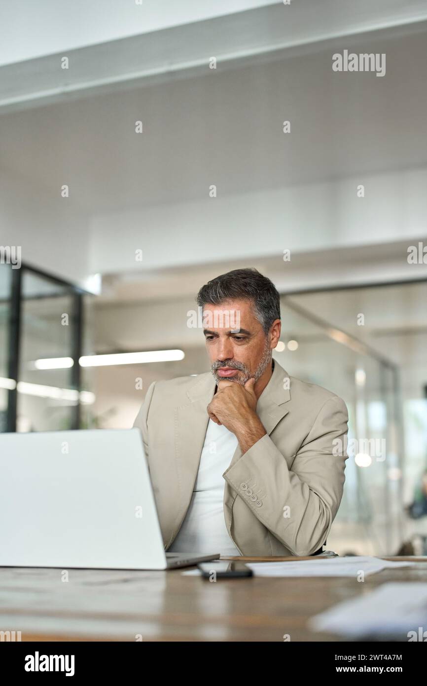 Homme d'affaires professionnel d'âge moyen concentré utilisant un ordinateur portable dans le bureau d'entreprise. Banque D'Images