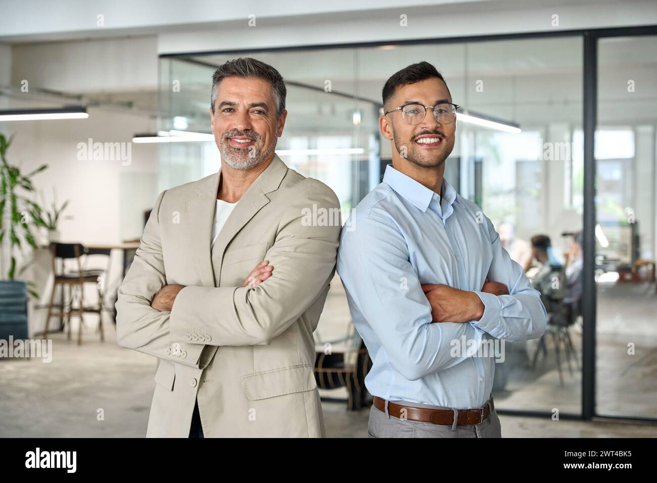 Deux partenaires commerciaux heureux debout dos à dos dans le bureau de l'entreprise. Portrait. Banque D'Images