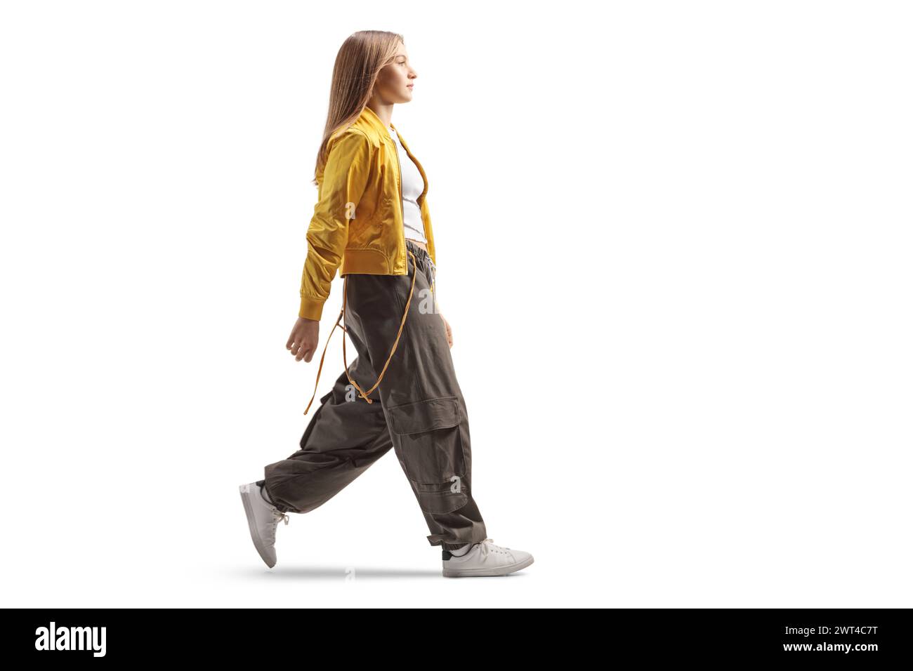 Plan de profil pleine longueur d'une adolescente à la mode marchant isolé sur fond blanc Banque D'Images