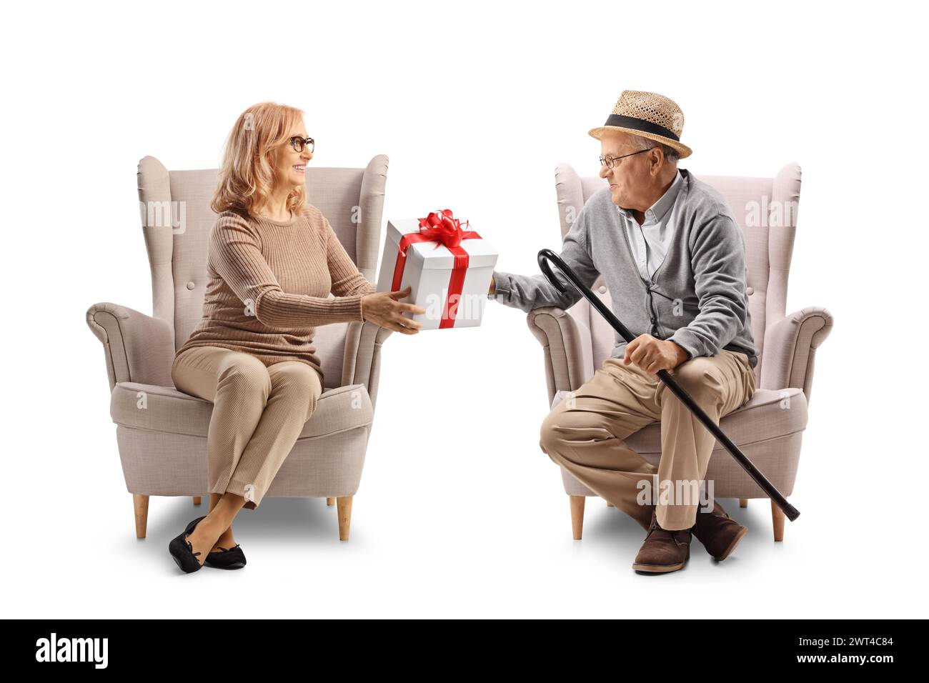 Femme d'âge moyen assise dans un fauteuil et donnant un cadeau à un homme âgé isolé sur fond blanc Banque D'Images