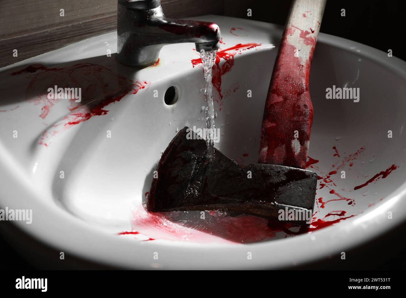 Hache avec du sang sous l'eau du robinet dans l'évier, gros plan Banque D'Images