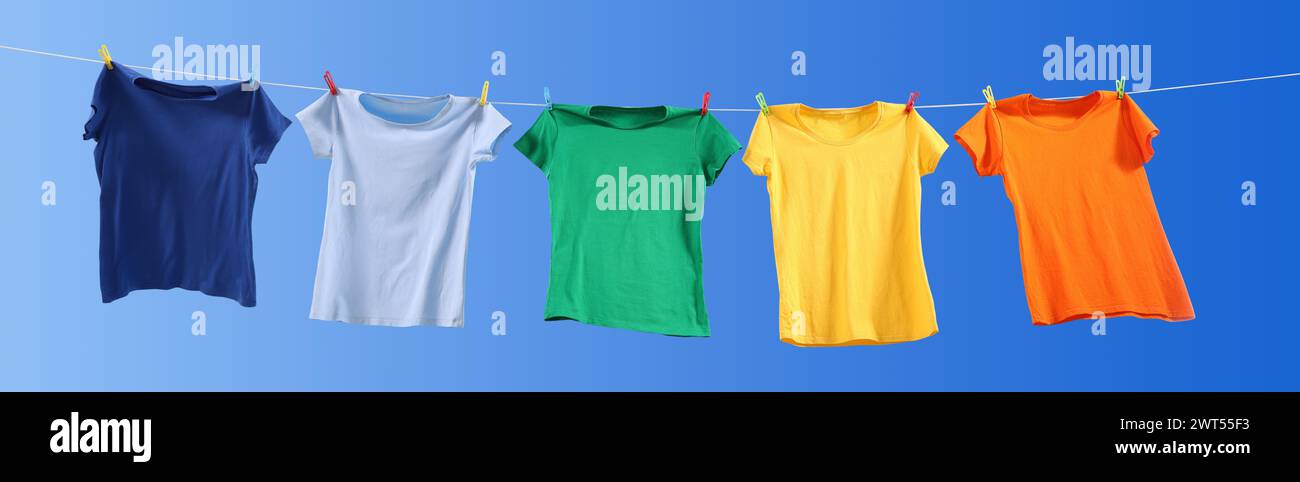 T-shirts colorés séchant sur la ligne de lavage contre le ciel bleu, vue d'angle bas. Conception de bannière Banque D'Images T-shirts colorés séchant sur la ligne de lavage contre le ciel bleu, vue d'angle bas. Conception de bannière Banque D'Images