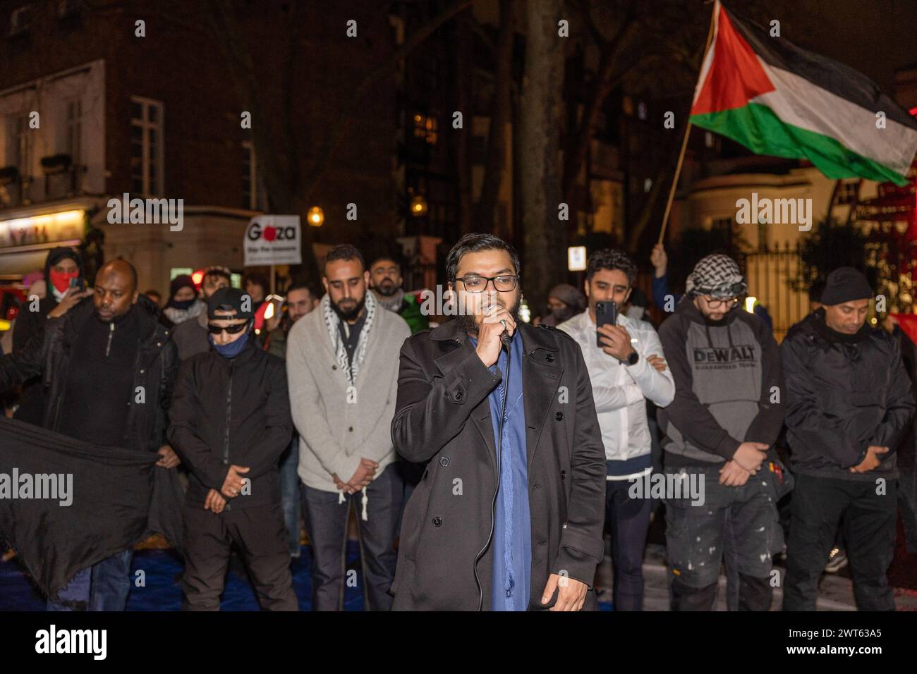 Londres, Royaume-Uni. 15 mars 2024. Imam est vu diriger les prières devant l'ambassade d'Arabie Saoudite à Londres pour la prière Taraweeh. Les partisans pro-palestiniens se rassemblent devant l'ambassade d'Arabie saoudite à Londres pour la prière Taraweeh le 4ème jour du Ramadan pour prier pour ceux qui ont souffert à cause de la guerre Israël-Hamas. Ils condamnent également le gouvernement saoudien pour ne pas avoir fait assez d'efforts pour aider à ramener la paix dans la région. Crédit : SOPA images Limited/Alamy Live News Banque D'Images