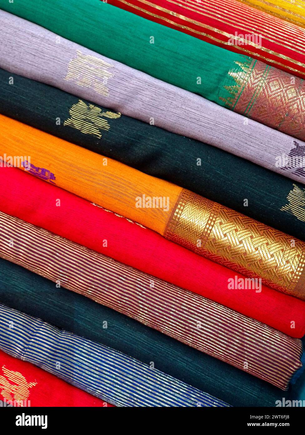 Vue rapprochée de saris ou de sarees empilés dans l'affichage d'un magasin de détail, pour une utilisation comme arrière-plan de textiles indiens. Banque D'Images