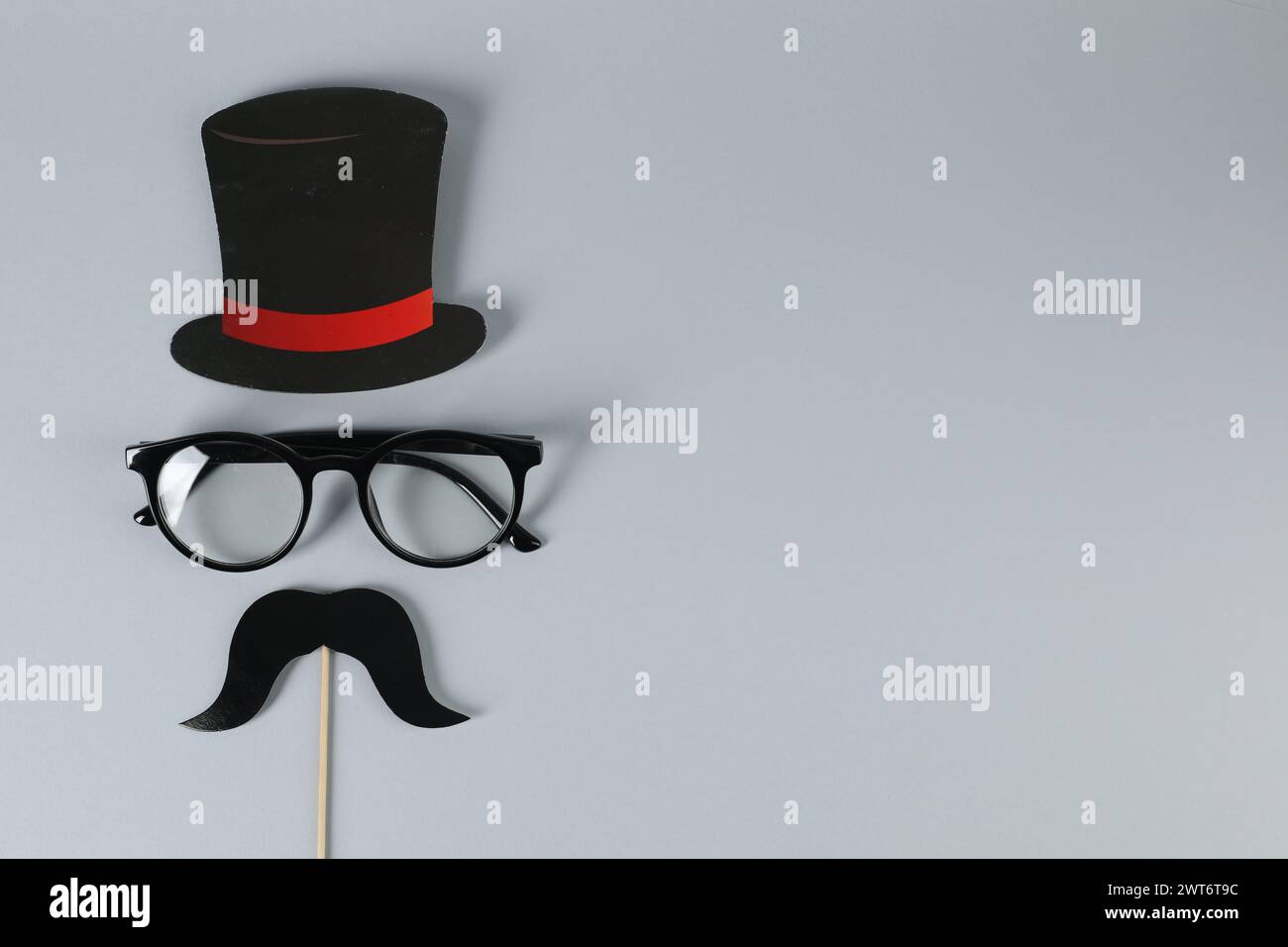 Fausse moustache avec accessoire de fête, chapeau en papier et lunettes sur fond gris, vue de dessus. Espace pour le texte Banque D'Images