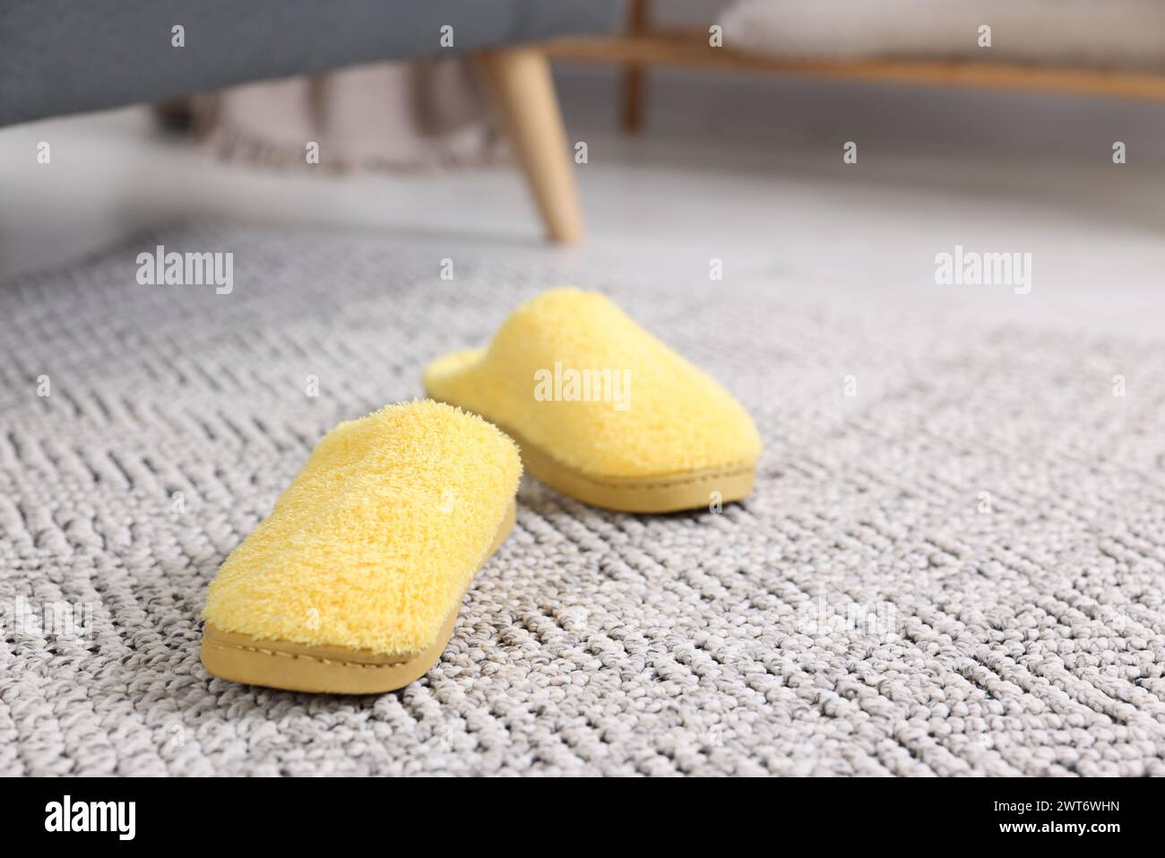 Chaussons jaunes doux sur tapis crochet à l'intérieur, gros plan Banque D'Images