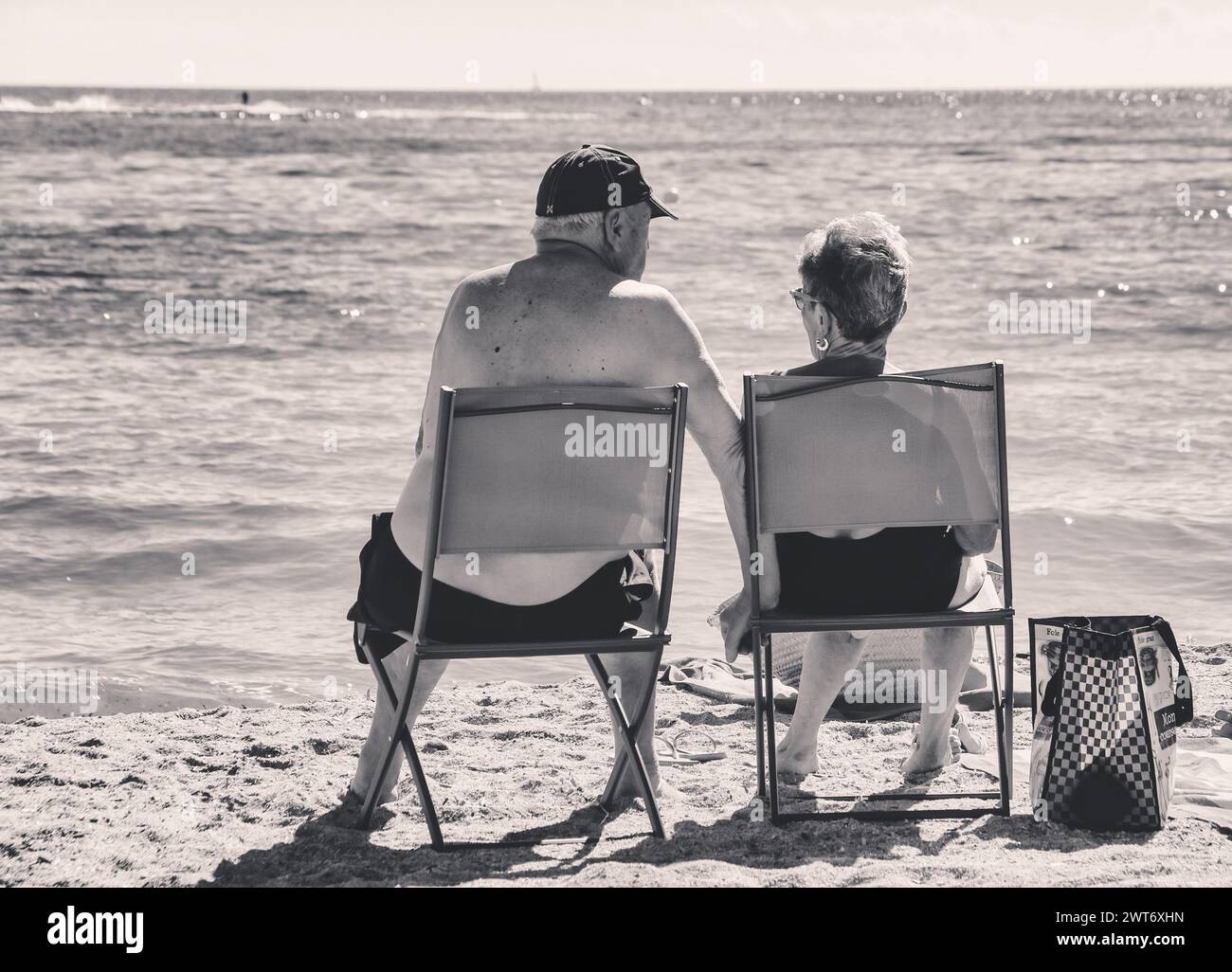 Sainte Maxime , France - 27 août 2020 : couple senior en maillot de bain assis sur des chaises en face de la mer sur la plage de la Côte d'Azur, noir et blanc Banque D'Images