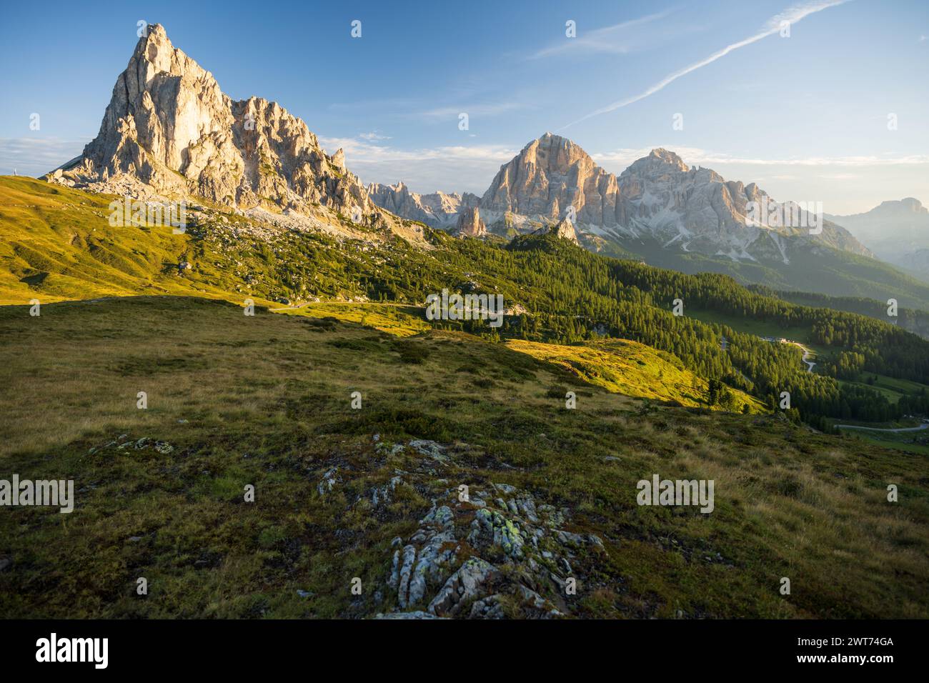 Lever de soleil à Passo Giau avec la route et les voitures garées et les campeurs avec le soleil briller à la prairie et les sommets pendant le matin d'été en août Banque D'Images