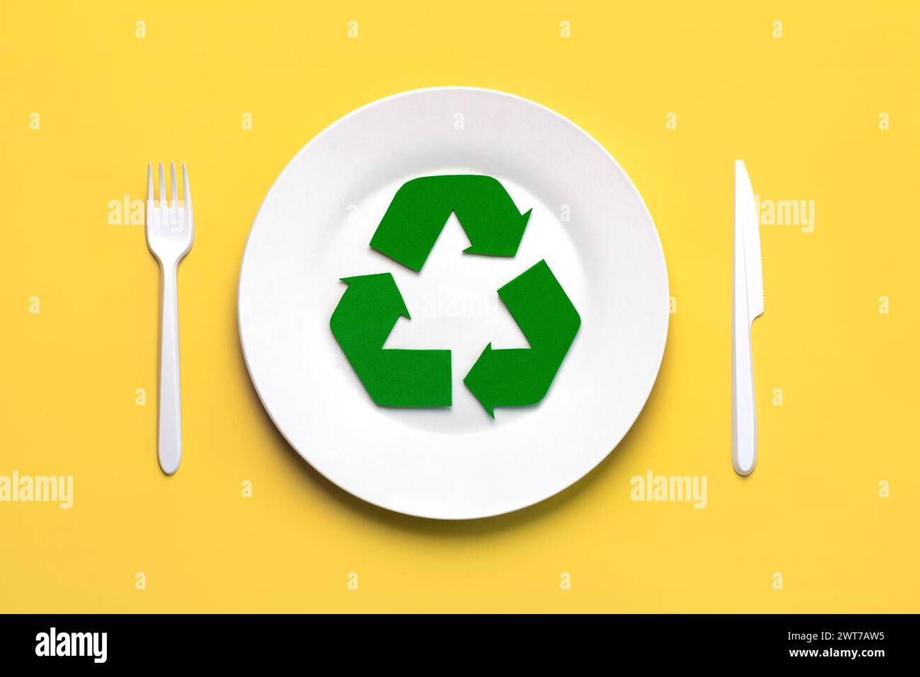 Vue de dessus du symbole de recyclage avec couverts en plastique blanc et assiette sur fond jaune. Concept de recyclage respectueux de l'environnement Banque D'Images