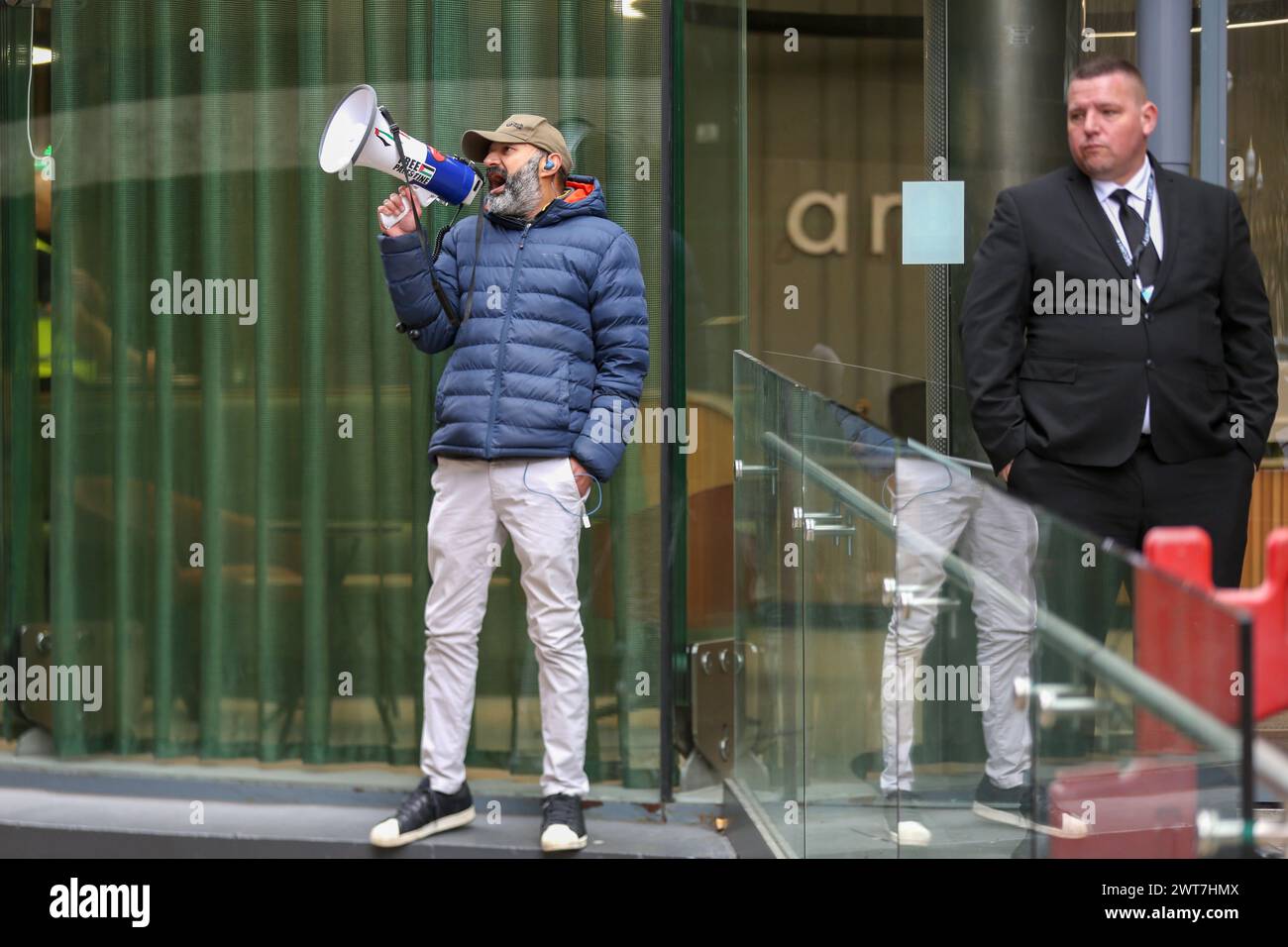 Un manifestant chante à travers un mégaphone, tandis qu'un garde de sécurité se tient debout pendant la manifestation. Les manifestants du Front de la jeunesse pour la Palestine (YFFP) et leurs partisans appellent au boycott d'AXA, affirmant qu'ils investissent plus d'un milliard de dollars dans des colonies illégales sur ce qui était autrefois des terres palestiniennes et détiennent des millions dans des investissements dans trois banques israéliennes. Ils déclarent avec ce soutien financier des sociétés comme AXA sont complices des crimes d'Israël contre les Palestiniens à Gaza et ailleurs. (Photo Martin Pope/SOPA images/SIPA USA) Banque D'Images