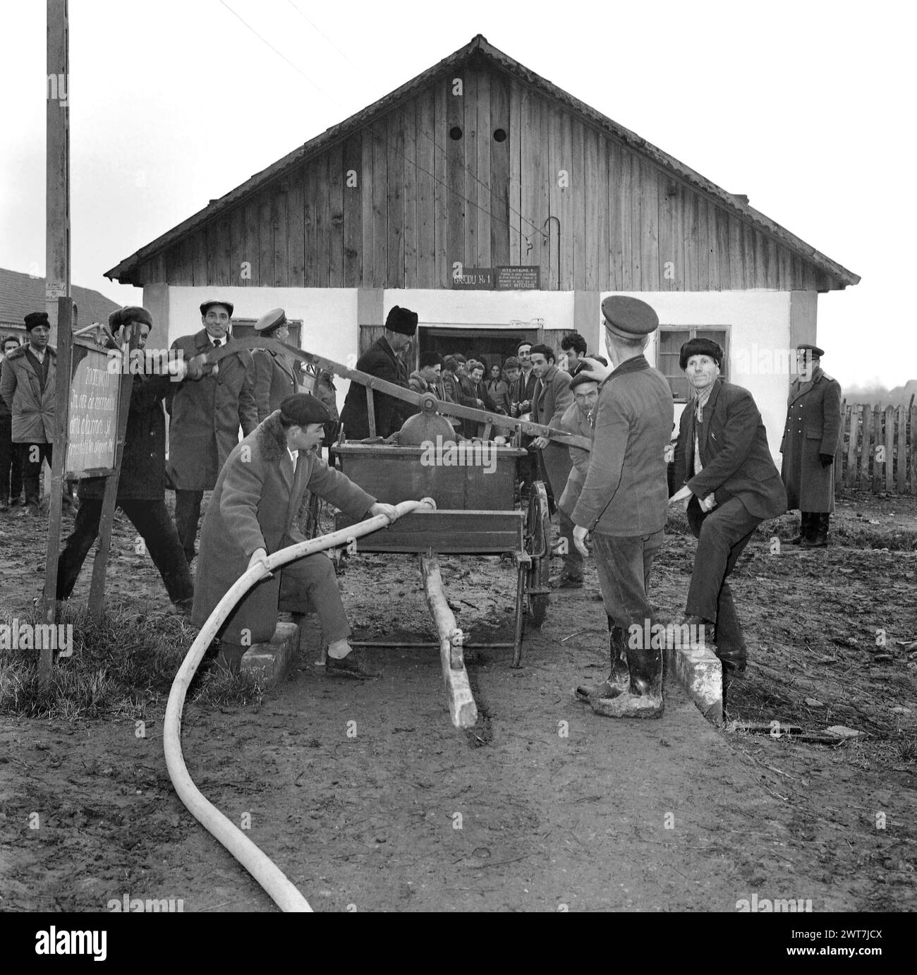 Une coopérative agricole d'Etat en Roumanie communiste, dans les années 1970 Groupe de paysans pratiquant comment faire fonctionner un wagon de pompiers avec une pompe à main, à utiliser en cas d'urgence incendie à la ferme collective. Banque D'Images