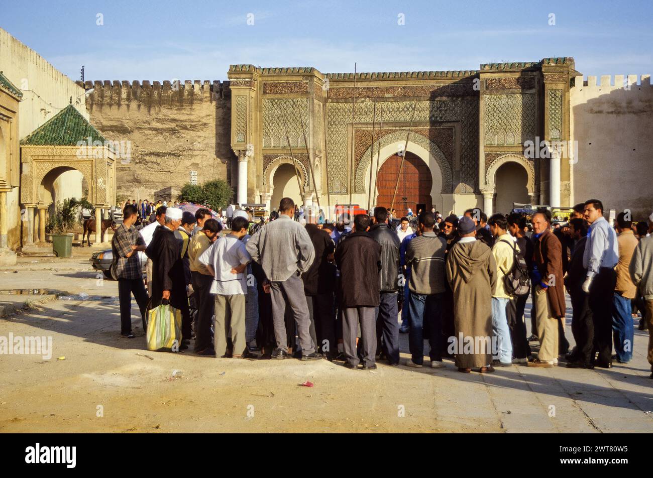 Meknès, Maroc. Place Hedime. Un public entoure un conteur. Bab Mansour en arrière-plan, construit 1672-1732, entrée du quartier impérial. Banque D'Images